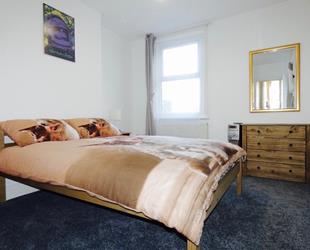 Bedroom with double bed, gold framed mirror and drawer unit