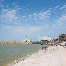 Looking along Margate defence steps to Turner Contemporary and harbour with a sailing yacht