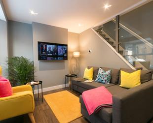 Adliv living room with bright sofa cushions, tv and glass staircase in Margate 