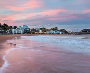 Sunset at Viking Bay, Broadstairs with pink and purple sky and waves across the beach