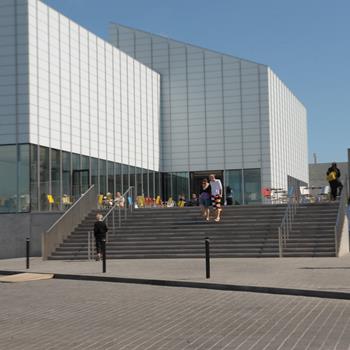 Couple walking down steps of Turner Contemporary, Margate with tables and chairs in the background