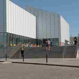 Couple walking down steps of Turner Contemporary, Margate with tables and chairs in the background