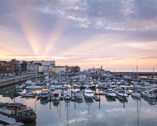 Sunrise over Ramsgate Royal Harbour boats with purple sky and rays of light above seafront buildings