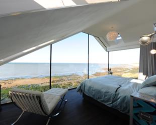 Full length bedroom windows with view of beach below. 